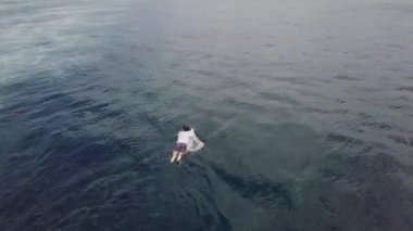 Sörf tahtasıyla okyanusta kürek çeken bir erkek sörfçünün yukarıdan aşağıya bakışı.