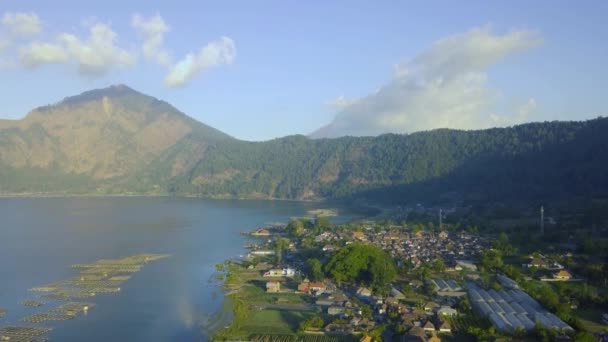 Göl ve dağ manzarası yakınlarındaki köy kırsal kesiminin havadan görünüşü. — Stok video