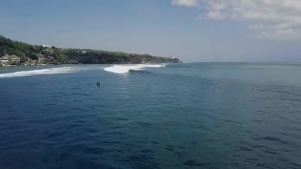 Cinematic aerial view over a surfer riding a breaking wave in the ocean at summer. — Stock Video