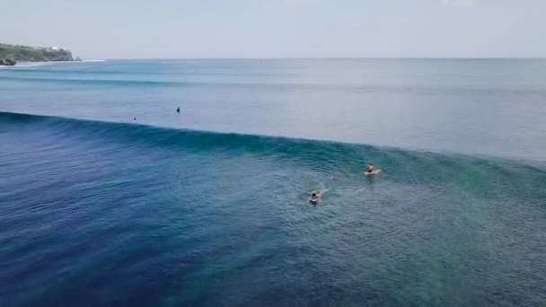 Vue aérienne cinématographique sur un surfeur chevauchant une vague déferlante dans l'océan en été . — Video