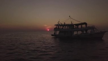 Günbatımında okyanusta bir tekne ve gün batımını gören bir hava aracı..