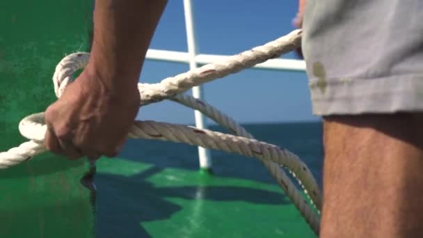 Onherkenbare man op een zeilboot die een touw knoop maakt. — Stockvideo