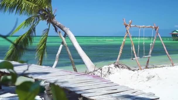 Pont en bois et balançoire à corde à la plage avec eau turquoise bleue et ciel bleu — Video