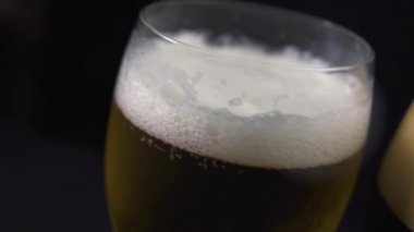 Karanlıkta köpüren beyaz şarap ve siyah şarap kadehlerinin yakın görüntüsü..