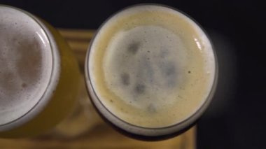 Tahta bir şarap uçağında köpüklü beyaz ve siyah şarap kadehlerinin üst görüntüsü..