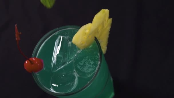 Un verre de cocktail à l'ananas, cerise rouge. Barman ajoutant des feuilles de menthe sur le dessus — Video