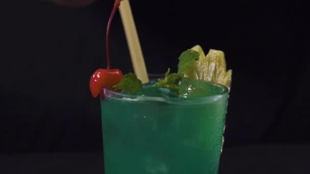 Bartenders hand putting a drinking straw in a glass of green tropical cocktail. — Stock Video