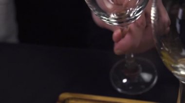 Bir adam şarap bardağına köpüklü beyaz şarap dolduruyor..
