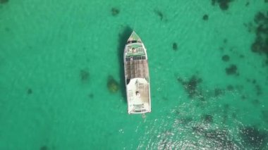 Yukarıdan aşağıya yaz günü yeşil gölde yüzen bir teknenin görüntüsü.