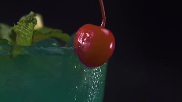 Macro tiro na borda superior de um copo de bebida cocktail verde em vidro rotativo . — Vídeo de Stock