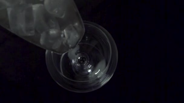 Вид зверху вниз, щоб залити кубики льоду в келих для вина на темному нічному фоні . — стокове відео