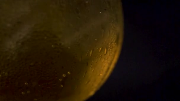 Plan macro d'un verre de boisson alcoolisée avec de la glace tournant à l'intérieur du verre. — Video