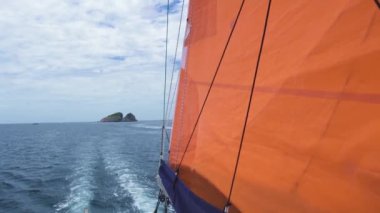 Tropikal adalarda seyahat eden yelkenli, suda izler ve dalgalar yaratır..