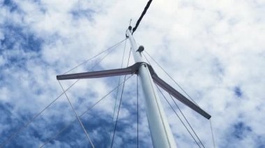 Mavi gökyüzüne ve beyaz bulutlara karşı yelkenli direğinin alt açısından bak.