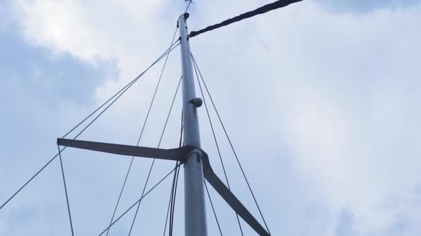 Le mât d'un voilier flottant dans l'océan contre les nuages brillants et le ciel.