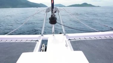 Mavi okyanusta adaya doğru ilerleyen beyaz yatın güverte manzarası.