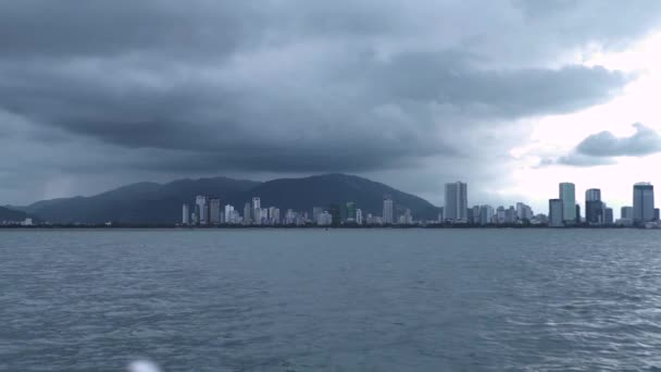 Skyline de la ciudad en una sombría vista del clima desde el ferry en movimiento en el océano. — Vídeos de Stock