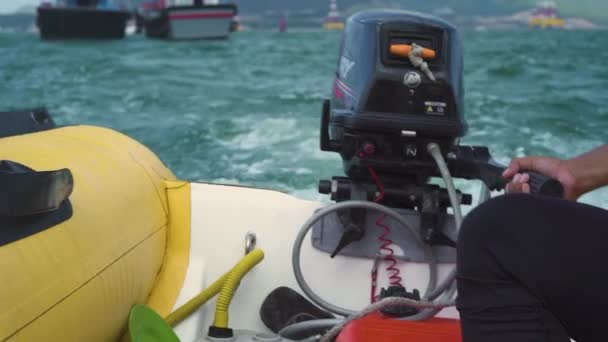 Zblízka pohled na muže, který ovládá motorový nafukovací člun v moři. — Stock video