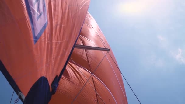 Oranžová hlavní plachta a pobyt plachta na plachetnici dolní úhel pohledu na pozadí oblohy. — Stock video