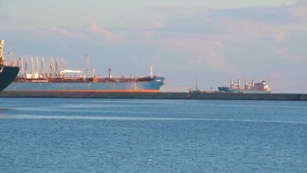 Lastfartyg med kranar tung lyft i hamn med lugnt blått hav och himmel bakgrund. — Stockvideo