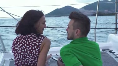 Sevecen genç çift yatın güvertesinde konuşuyor ve gülümsüyor.