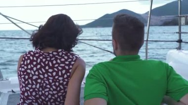 Yatın ön güvertesinde oturan bir çiftin arka portresi..