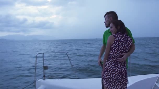 Dulce pareja de pie cubierta del barco, abrazándose y mirándose el uno al otro y el mar. — Vídeos de Stock