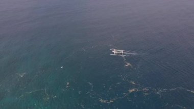 Yazın mavi okyanusta yükselen küçük bir teknenin gerçek zamanlı görüntüsü..