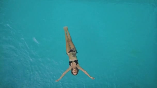 Veduta aerea di una donna sexy in bikini che galleggia sul retro rilassandosi in piscina — Video Stock