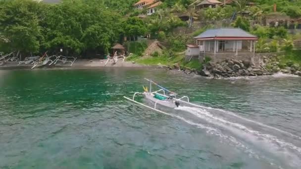 Nagranie drona nad małą łodzią zbliżającą się do brzegu morza i doków na piasku. — Wideo stockowe