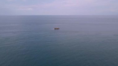 Drone görüntüleri: Turist teknesi sakin mavi okyanustan ufka doğru yükseliyor.