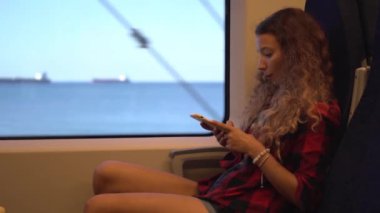 Trende akıllı telefonlu, kırmızı kareli gömlekli esmer.