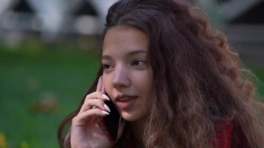 Şık genç kadın elinde akıllı telefonla konuşuyor.