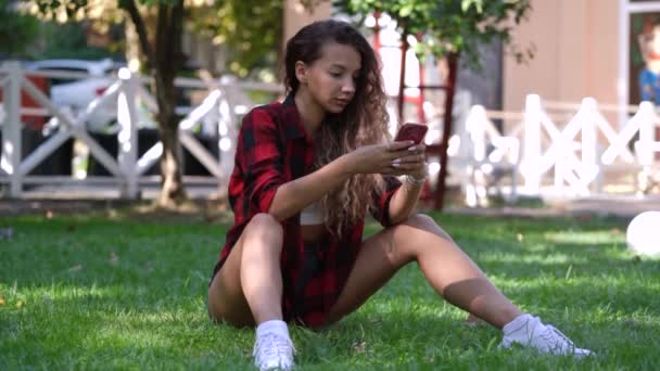 Junge Frau in rot-kariertem Hemd tippt auf Handy — Stockvideo