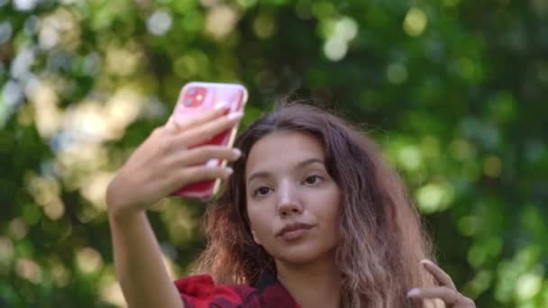 Modische junge Frau im karierten Hemd fixiert lockiges Haar — Stockvideo