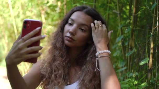 エレガントな女性は公園で赤いスマートフォンを保持自撮り — ストック動画