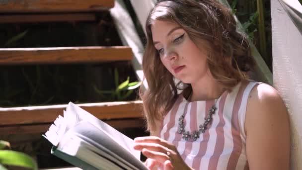 Νεαρή γυναίκα γυρίζει σελίδα βιβλίου με τατουάζ χέρι closeup — Αρχείο Βίντεο