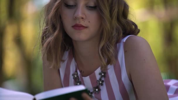ゆったりとした巻き毛のあるファッショナブルな女性はぼやけた本を読みます — ストック動画