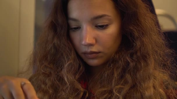 Konzentrierte junge Frau mit langen lockigen Haaren in Nahaufnahme — Stockvideo