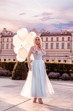 Kalenin yanında balonları olan güzel bir kadın.