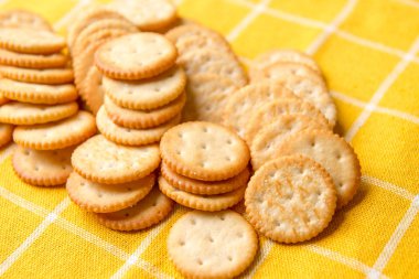 Tuzlu Yuvarlak Kraker. Kraker Yığını. Kazık Sütunu. Kurabiye krakeri. sarı masa örtüsü.