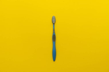 Sarı arka plan üzerinde dişler için bir mavi gri diş fırçası.