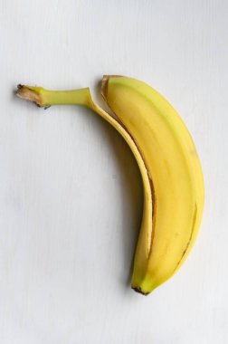 Olgun bir muzun yediği sarı kabuk. Beyaz ahşap arka planda meyveler.