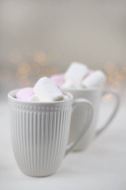 Sıcak kış içeceği, kakaolu ve fincanlarda marshmallowlu, tahta beyaz arka planda, Noel çelenkli. Üst görünüm.