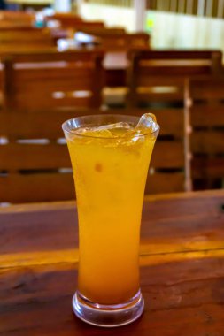 Buzla dolu uzun bir bardak portakal suyu ahşap bir masada oturur.