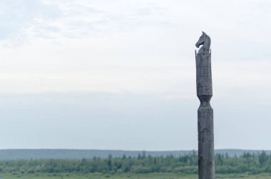 Bir at Serge ile Yakut kutup bulutların altında sonsuz tundra ve orman arka planda bir uçurumun üzerinde ahşaptan yapılmış bir at kafası ile duruyor. 