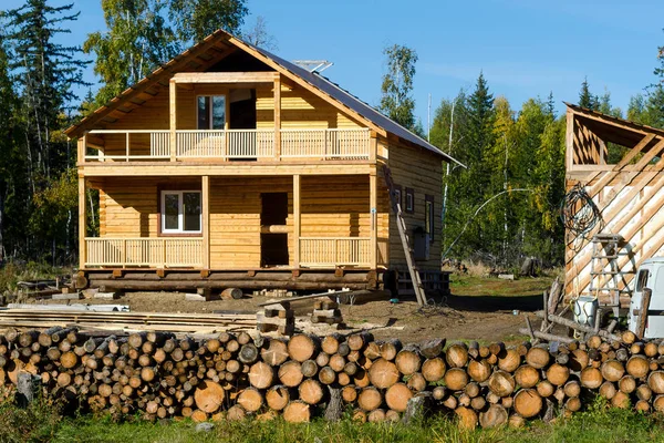 A new private residential building made of yellow pine logs stands unfinished among spruce forests and firewood for burning wild forest in the tundra of Yakutia, in the recently developed territory in the village of ulus Suntar.