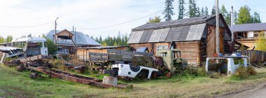 Arabaların birçok terk demir binalar konut ahşap evler arasında bir çöp Yakutia Kuzey köyünde yatıyor.