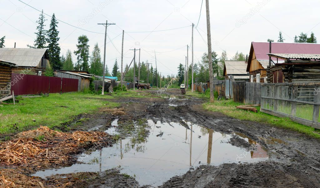 A large puddle of mud on a residential street in the Northern Yakut village in the forest.
