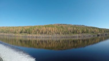 Teknewake su izi Yansıması ile dağ ve mavi su üzerinde ormanın sarı köknar ağaçları geçmiş Yakutia Viluy taiga nehri boyunca gider.